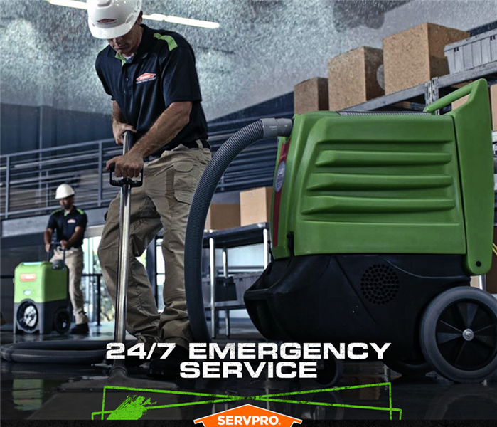 SERVPRO crew extracting water from a flooded business with the caption: "24/7 Emergency Service"